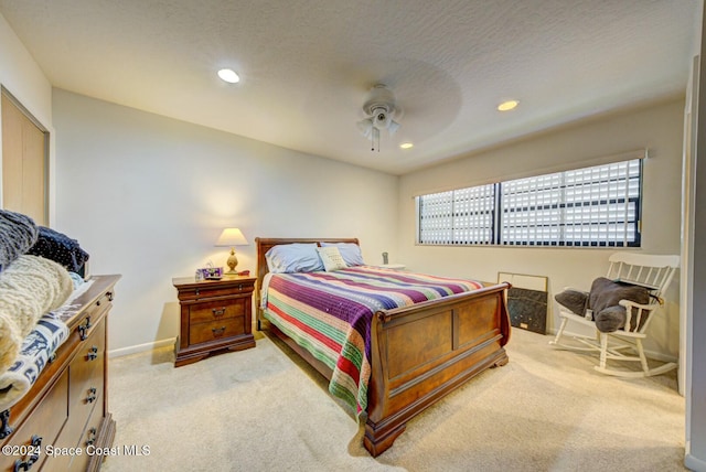 bedroom featuring ceiling fan, light carpet, and a textured ceiling