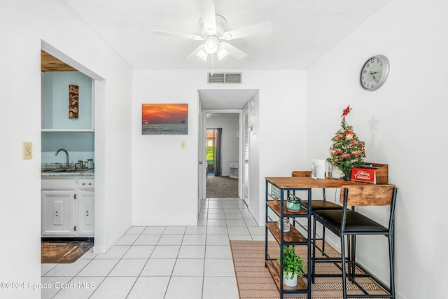 interior space with ceiling fan, sink, light tile patterned flooring, and a textured ceiling