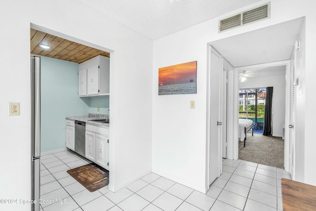 kitchen featuring stainless steel dishwasher, white cabinetry, and a textured ceiling