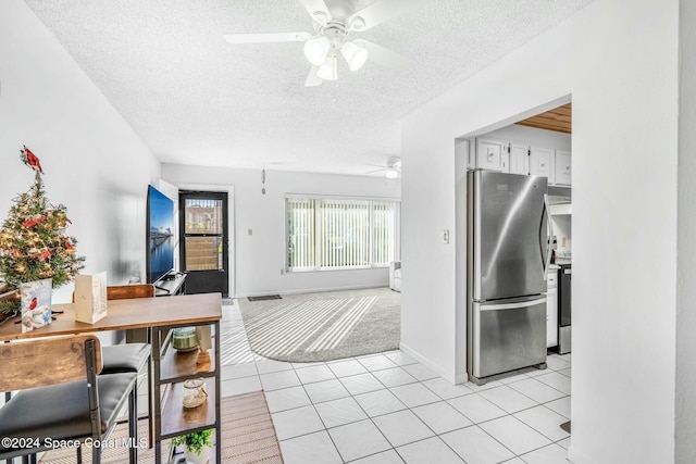 kitchen featuring ceiling fan, white cabinets, a textured ceiling, light tile patterned floors, and appliances with stainless steel finishes