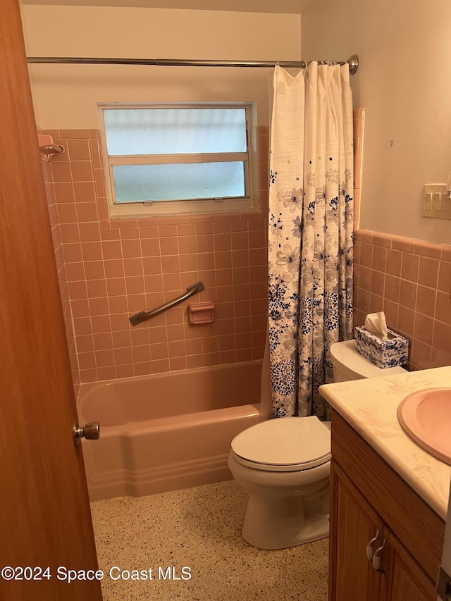 full bathroom with tile walls, toilet, vanity, and shower / bath combination with curtain