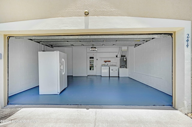 garage featuring separate washer and dryer and white refrigerator with ice dispenser