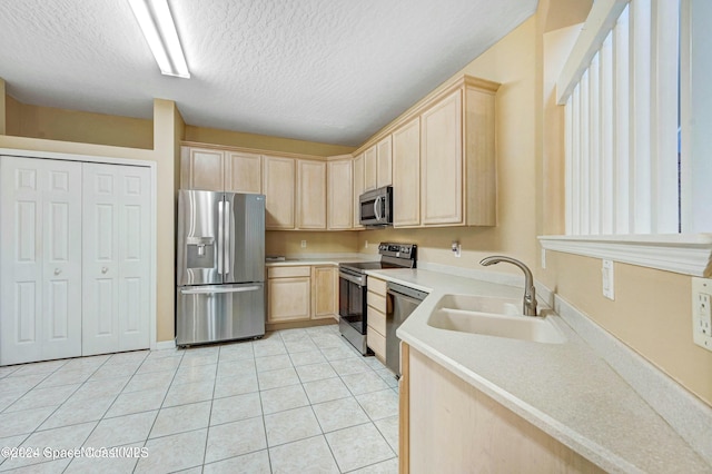 kitchen with sink, light brown cabinetry, light tile patterned flooring, and appliances with stainless steel finishes