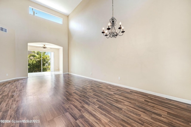 empty room featuring ceiling fan with notable chandelier, dark hardwood / wood-style flooring, and high vaulted ceiling