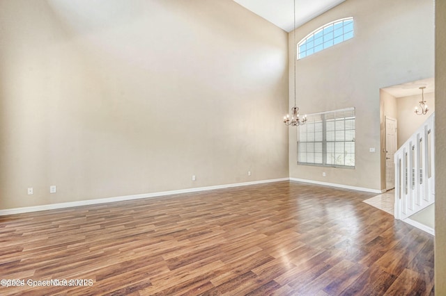 interior space featuring hardwood / wood-style floors, a towering ceiling, and an inviting chandelier