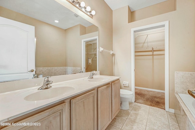 bathroom featuring tile patterned flooring, vanity, toilet, and tiled bath