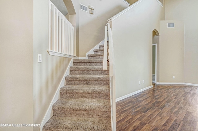 stairs featuring wood-type flooring and a towering ceiling