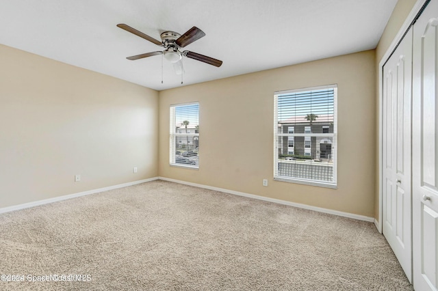 unfurnished bedroom with carpet, a closet, multiple windows, and ceiling fan