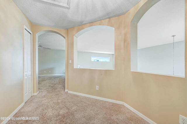 hall featuring carpet and a textured ceiling