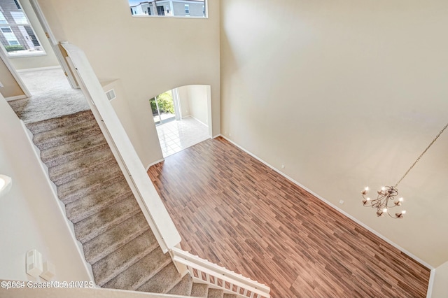 foyer featuring hardwood / wood-style flooring, a towering ceiling, and a chandelier