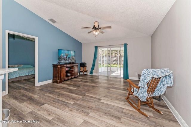 living area featuring lofted ceiling, a textured ceiling, wood-type flooring, and ceiling fan