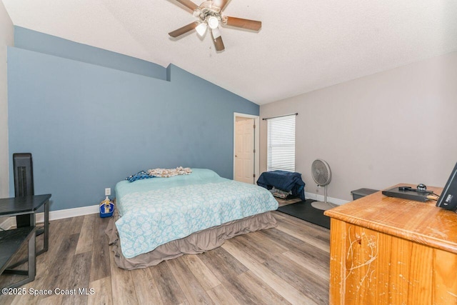 bedroom with ceiling fan, vaulted ceiling, hardwood / wood-style floors, and a textured ceiling