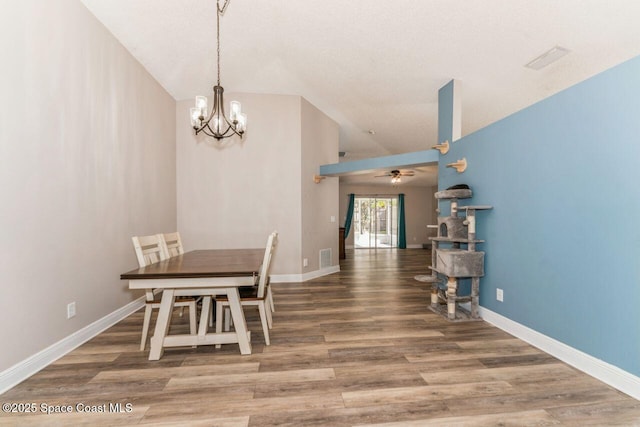 unfurnished dining area with ceiling fan with notable chandelier, wood-type flooring, and vaulted ceiling