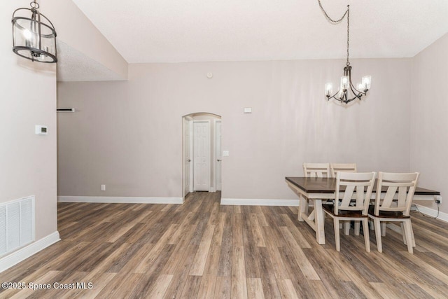 dining area with dark wood-type flooring and a chandelier