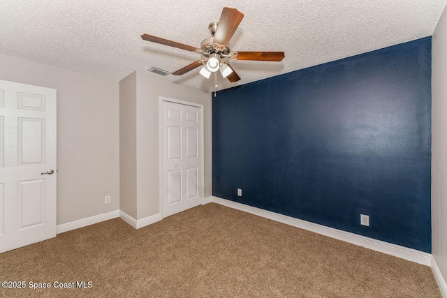 empty room with ceiling fan, carpet, and a textured ceiling