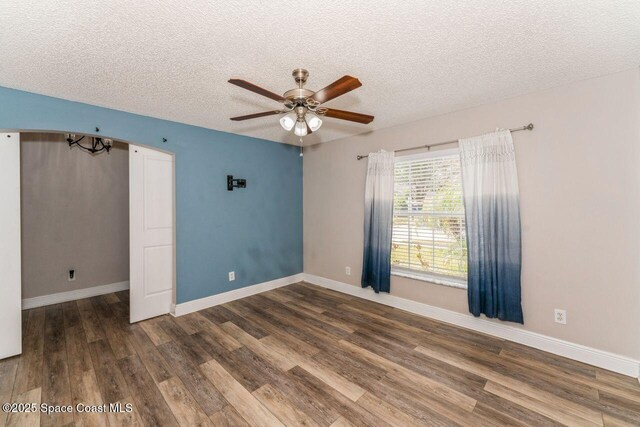 unfurnished room with ceiling fan, dark wood-type flooring, and a textured ceiling