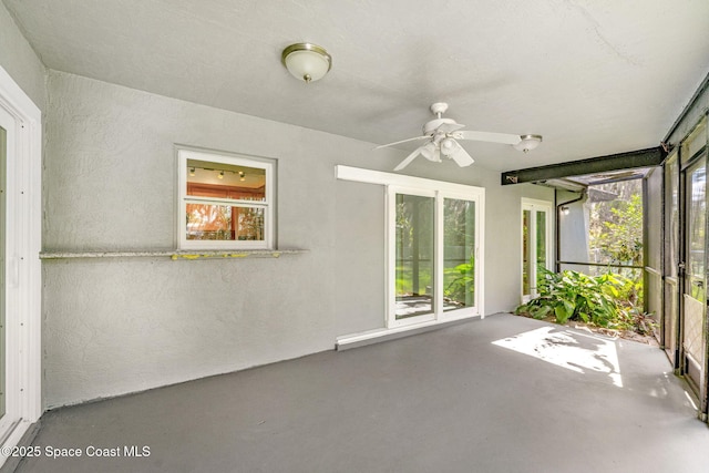 unfurnished sunroom with ceiling fan