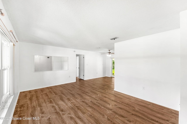 empty room with ceiling fan, a textured ceiling, and hardwood / wood-style floors