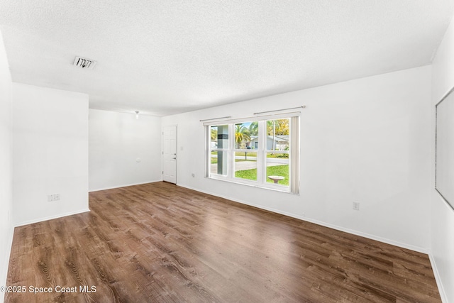 empty room with hardwood / wood-style flooring and a textured ceiling