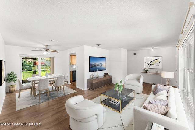 living room with light wood-type flooring, ceiling fan, and a textured ceiling