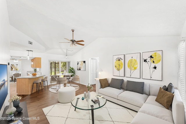 living room with vaulted ceiling, ceiling fan, and light hardwood / wood-style flooring