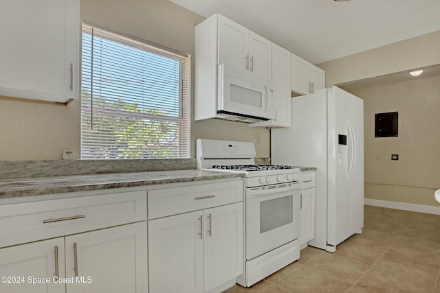 kitchen featuring white appliances, light tile patterned floors, stone counters, white cabinets, and electric panel