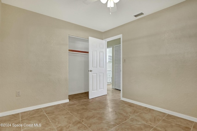 unfurnished bedroom with ceiling fan, a closet, and light tile patterned floors