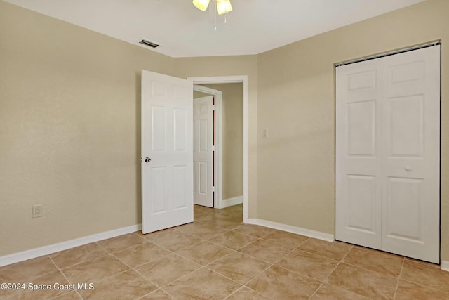 unfurnished bedroom with ceiling fan, a closet, and light tile patterned floors