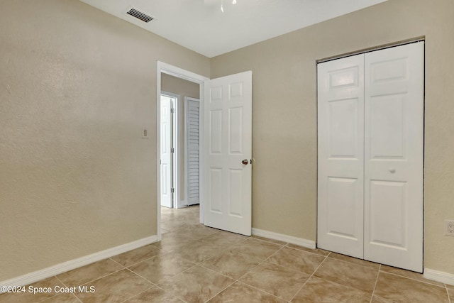 unfurnished bedroom with light tile patterned flooring and a closet