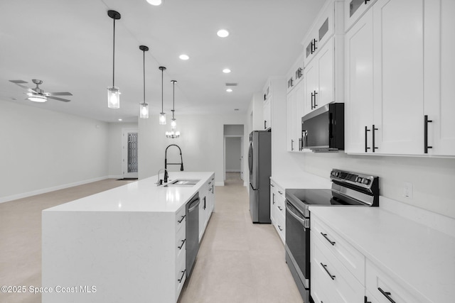 kitchen with pendant lighting, appliances with stainless steel finishes, sink, white cabinetry, and a center island with sink