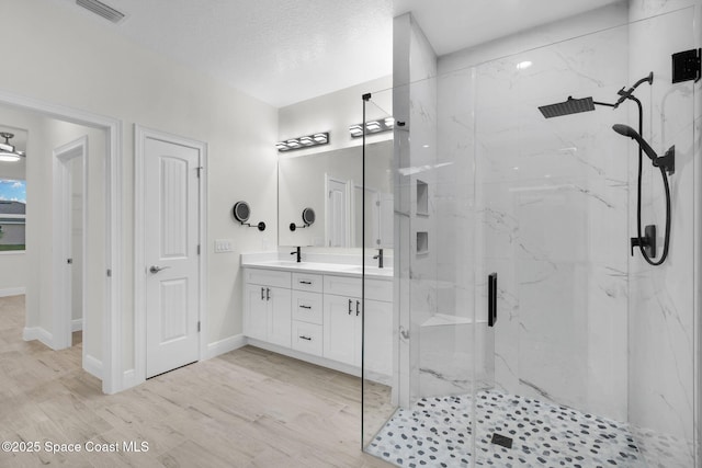 bathroom with vanity, a textured ceiling, a shower with door, and wood-type flooring