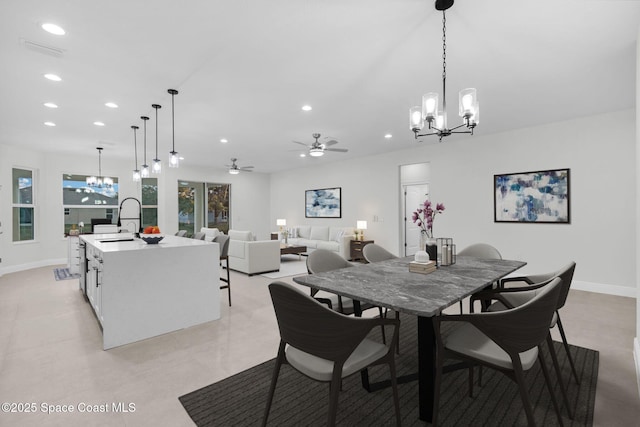 dining space featuring sink and ceiling fan with notable chandelier