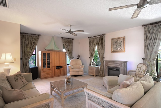 carpeted living room with a textured ceiling, a wealth of natural light, and ceiling fan