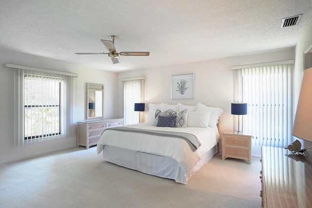 bedroom featuring ceiling fan, a textured ceiling, and light carpet