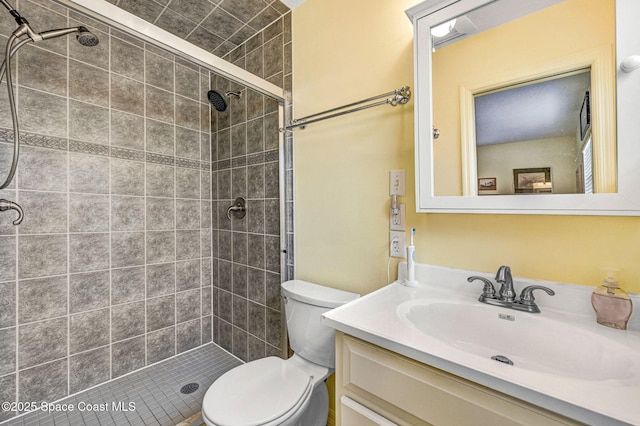 bathroom featuring a tile shower, vanity, and toilet