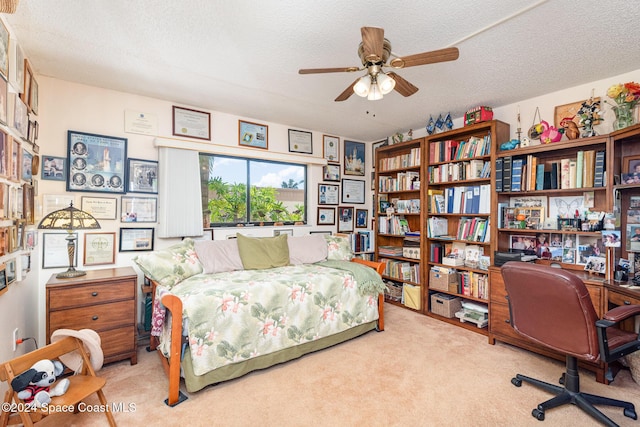 bedroom featuring a textured ceiling, light colored carpet, and ceiling fan