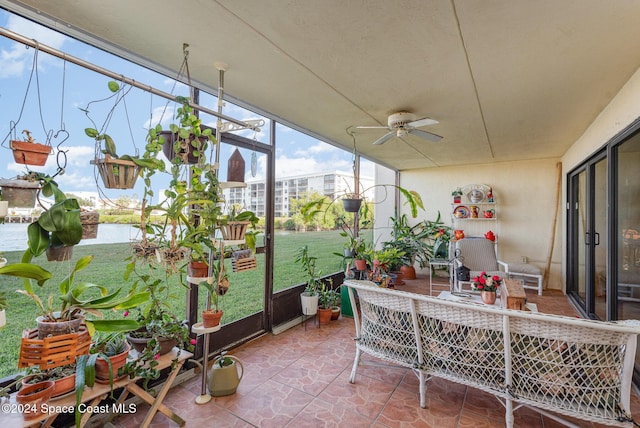 sunroom / solarium featuring ceiling fan and a water view