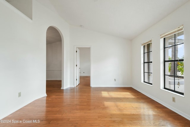 empty room with light hardwood / wood-style flooring and lofted ceiling