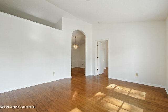 empty room with a chandelier, wood-type flooring, and high vaulted ceiling