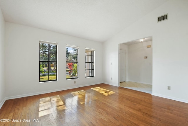 empty room featuring wood-type flooring and vaulted ceiling