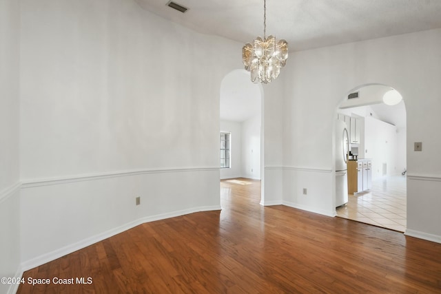 spare room featuring an inviting chandelier and light hardwood / wood-style flooring