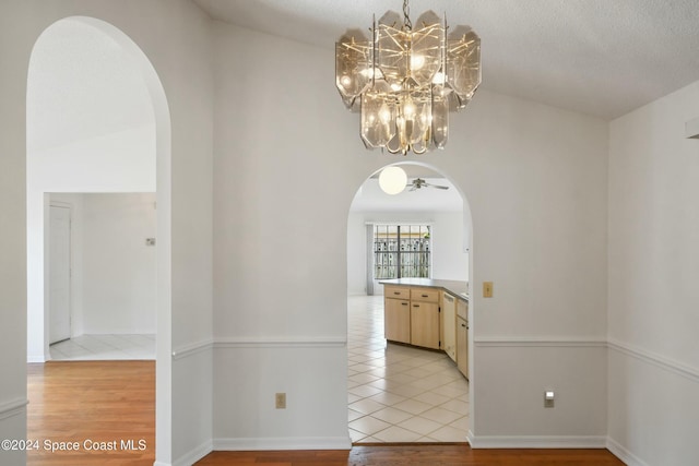 hallway featuring a textured ceiling, light hardwood / wood-style flooring, and vaulted ceiling