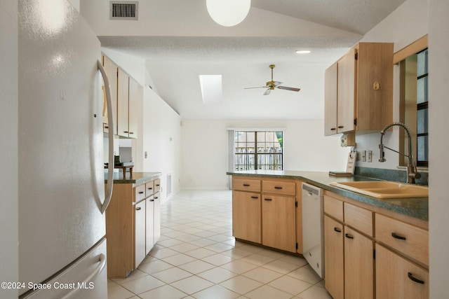 kitchen featuring ceiling fan, sink, kitchen peninsula, white appliances, and vaulted ceiling with skylight