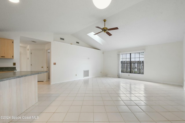 interior space with ceiling fan, vaulted ceiling with skylight, and light tile patterned flooring