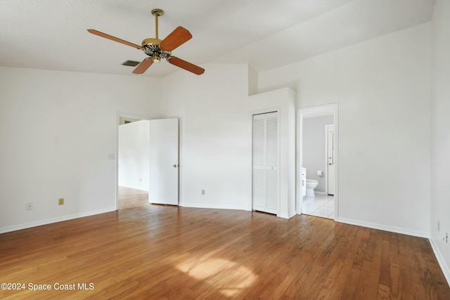 empty room with ceiling fan, high vaulted ceiling, and light hardwood / wood-style flooring