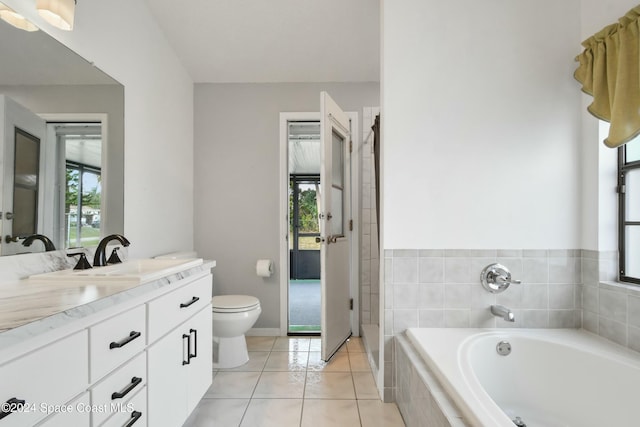 bathroom featuring tile patterned floors, vanity, tiled bath, and toilet