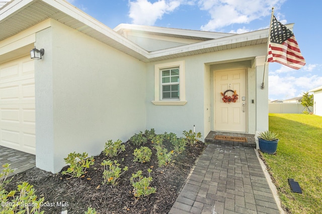 doorway to property featuring a lawn and a garage