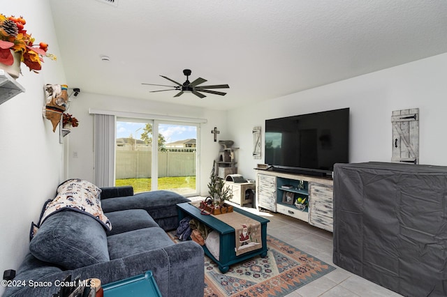 living room with tile patterned floors, ceiling fan, and a textured ceiling