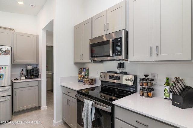 kitchen with appliances with stainless steel finishes, light tile patterned floors, and gray cabinetry