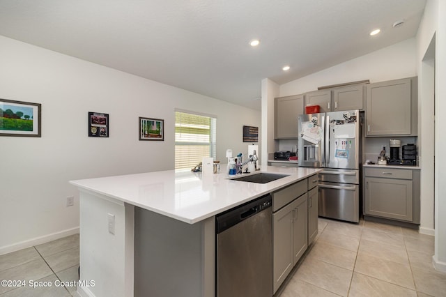 kitchen featuring sink, stainless steel appliances, vaulted ceiling, gray cabinets, and a center island with sink